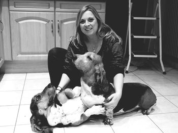 Portrait of young woman with dog sitting at home