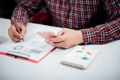 Midsection of man using mobile phone on table