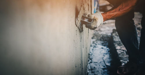 Low section of man plastering wall