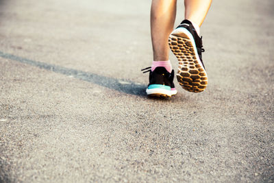 Low section of woman walking on road