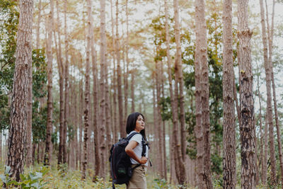 Side view of woman standing at forest