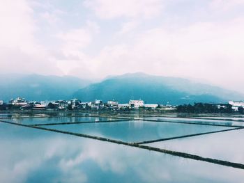 Scenic view of lake by town against sky