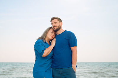 Couple embracing while standing against sea