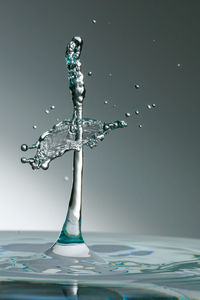 Close-up of drop falling on water against white background