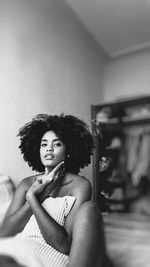 Young woman looking at camera while sitting in mirror