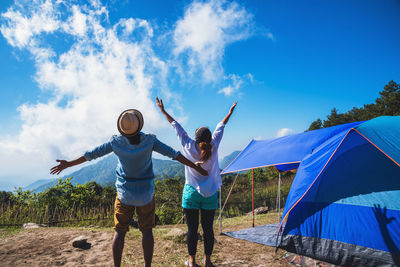 Low angle view of friends standing against blue sky