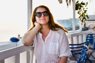 Portrait of young woman wearing sunglasses while sitting at home