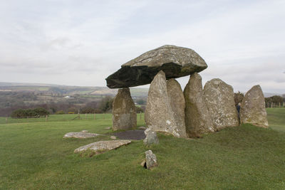 Rock formations on grassy field against sky