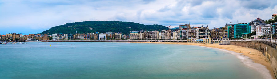 Buildings by sea against sky