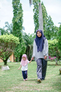 Full length of mother and daughter against trees