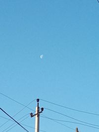 Low angle view of electricity pylon against blue sky