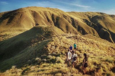 Rear view of people walking on mountain against sky