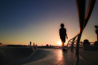 Silhouette boy on skateboard at park