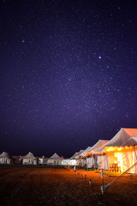 Scenic view of illuminated tents against sky at night