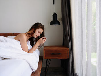 Portrait of young woman sitting on bed at home