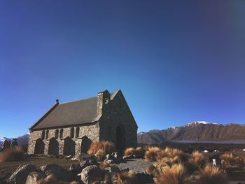 Building by mountain against clear blue sky