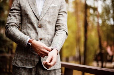 Midsection of well-dressed man standing in park