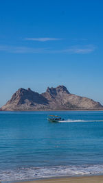 Scenic view of sea and mountains against blue sky