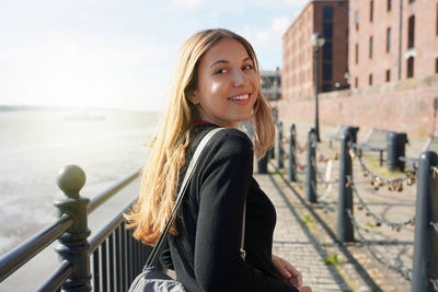 Portrait of beautiful woman smiling to the camera walking on liverpool promenade, united kingdom