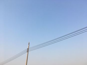 Low angle view of electricity pylon against clear sky