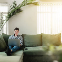 Man using mobile phone while sitting on sofa at home