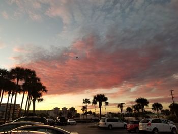 Cars on road against dramatic sky during sunset