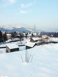 Snow covered houses by buildings against sky