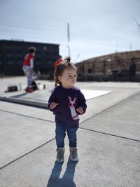 Full length of girl standing on street against sky