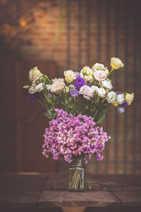 A bouquet of purple flowers in a glass vase on a wooden floor boards of old vintage. the home decor