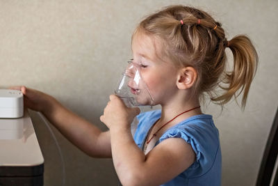 Side view portrait of a boy drinking glass at home