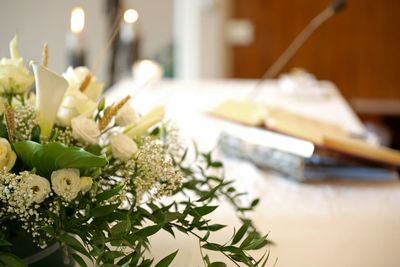 Vase of many flowers over an altar in the church and the holy bible on background