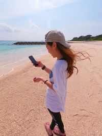 Woman standing at beach against sky