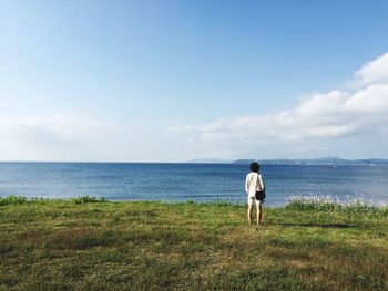 Rear view of man standing by sea against sky