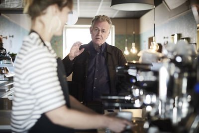 Male customer ordering female barista at cafe counter