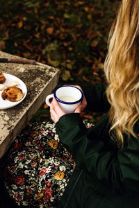 High angle view of woman holding coffee cup on table