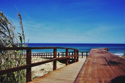 Jetty over sea against clear blue sky