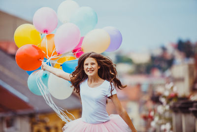 Full length of a smiling young woman holding balloons