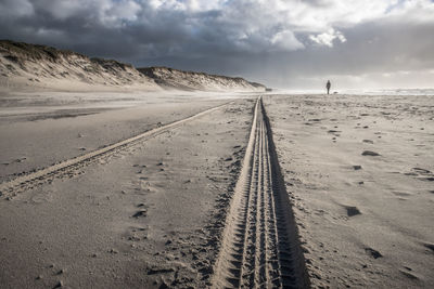 Tire tracks on beach against sky