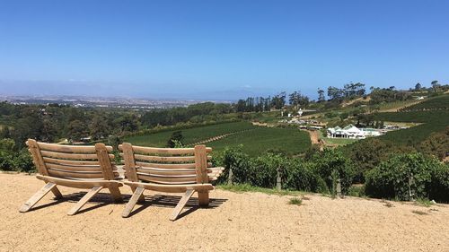 Empty chairs on beach against clear sky