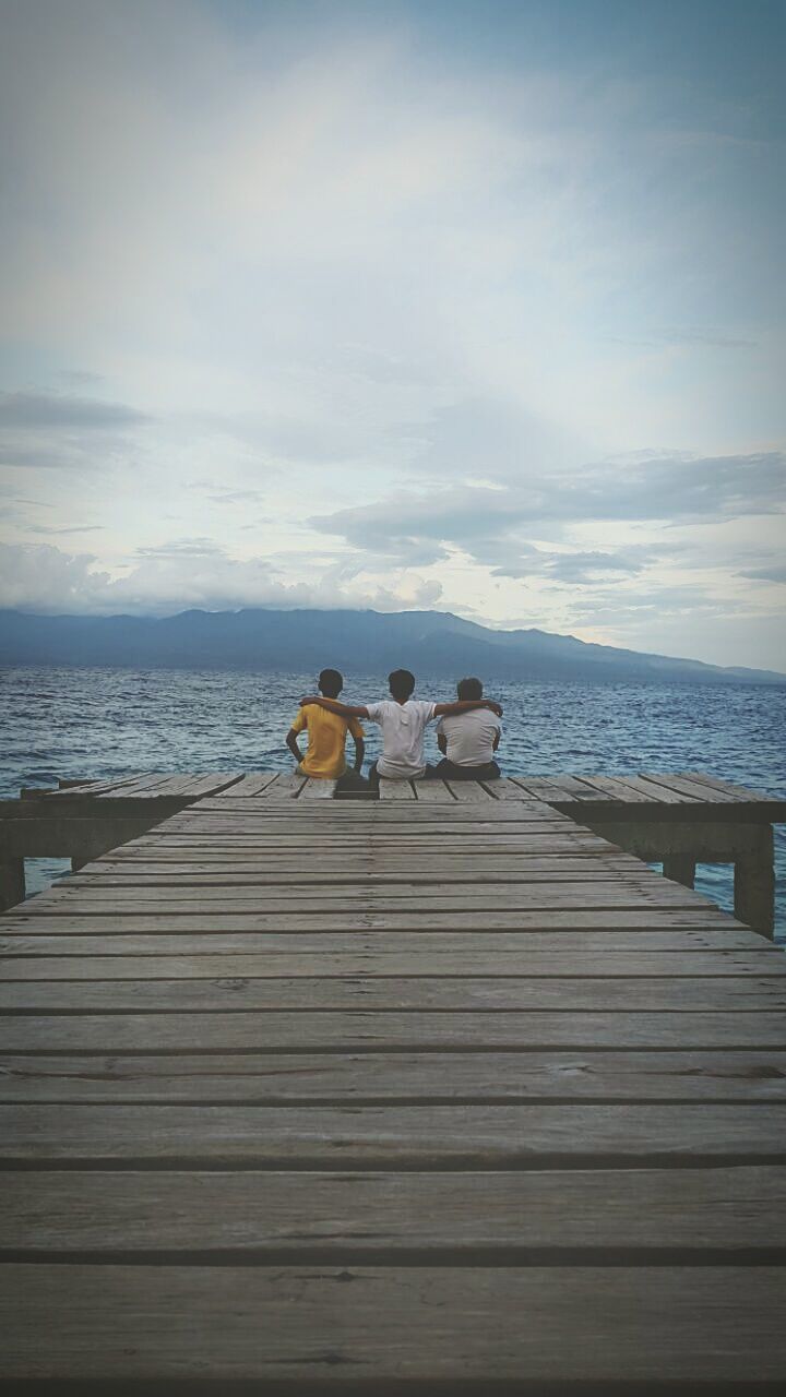 sea, water, sky, horizon over water, pier, wood - material, lifestyles, tranquil scene, leisure activity, men, tranquility, cloud - sky, scenics, beach, relaxation, boardwalk, togetherness, rear view