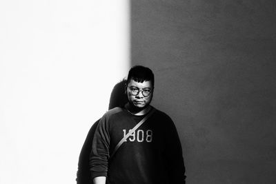 Portrait of young man standing against wall