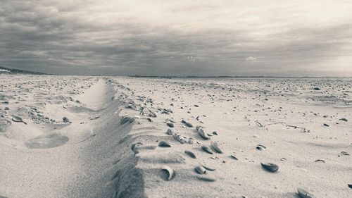 Footprints on sand at beach against sky