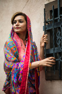 Confident beautiful woman in traditional cloths standing against wall