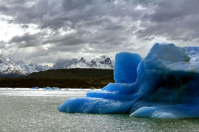 Ice floating on water in lake against sky