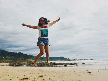 Full length of young woman at beach against sky