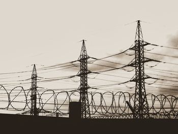 Low angle view of silhouette electricity pylon against sky