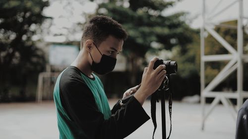 Man photographing with camera while sitting outdoors