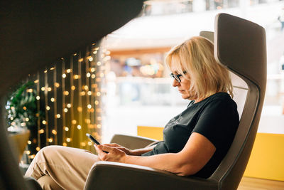 Senior woman using smart phone sitting on chair