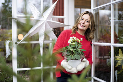 Smiling woman holding flower in pot