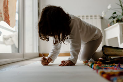 Side view of girl drawing on paper